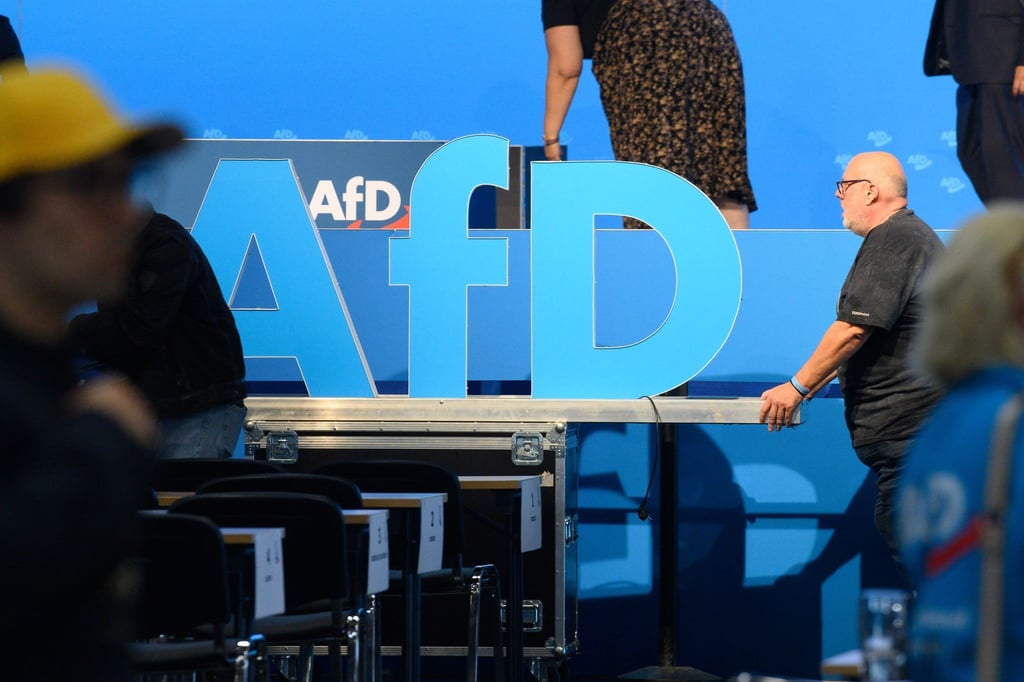 Helfer schieben nach der AfD Europawahlversammlung das AfD Logo aus der Halle.