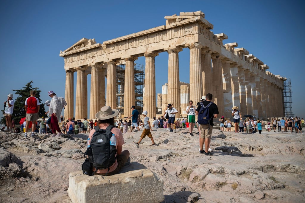 Touristen in Athen gehen an einem heißen Tag bei ihrem Besuch des Parthenon-Tempels auf dem Akropolis-Hügel.