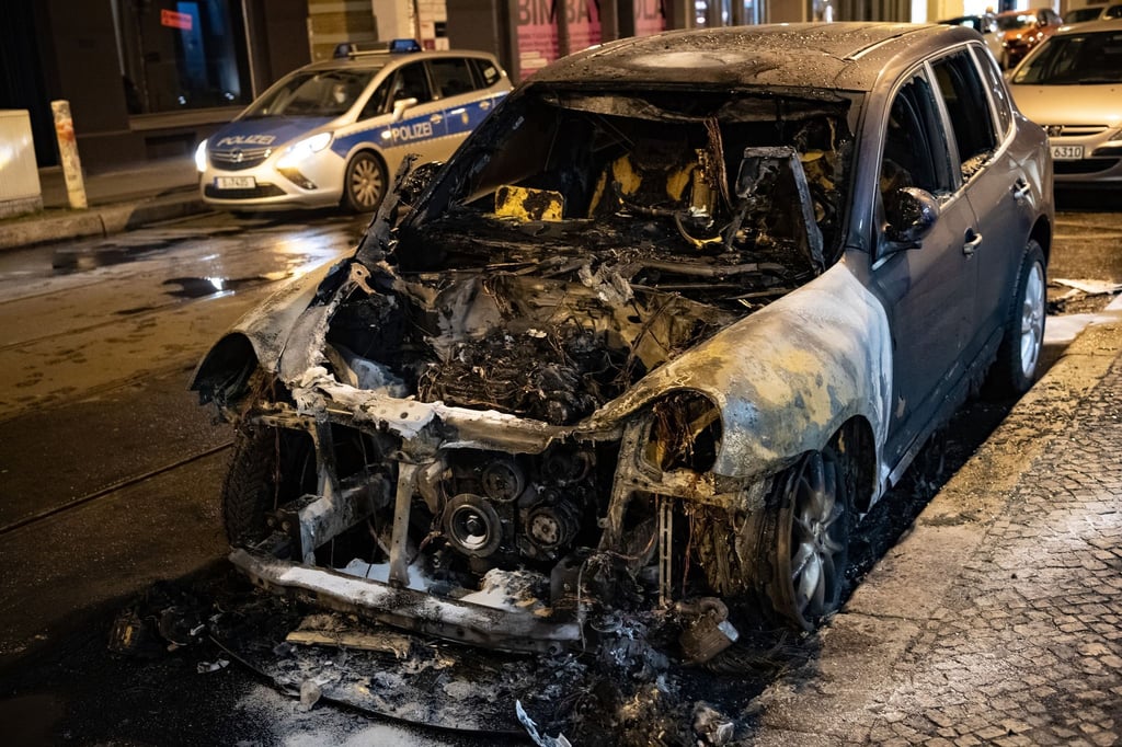 Ein ausgebranntes Auto steht auf einer Straße.