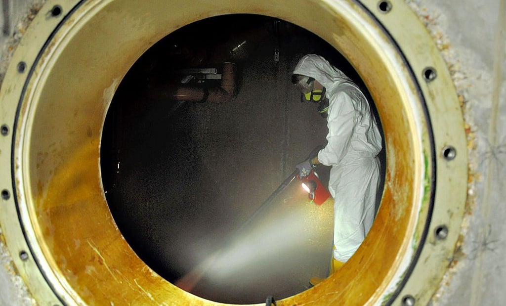 Derweil kümmert sich der Auszubildende Fabian Blohm in Schutzkleidung um die Reinigung eines sogenannten Schwallwasserbehälters.