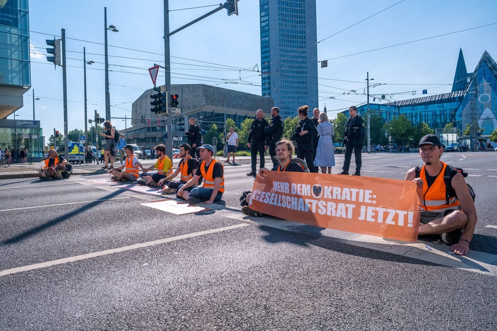 17 Angehörige der Letzen Generation haben sich am Montag an drei stellen auf dem Leipziger Augustplatz geklebt.