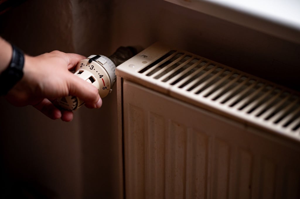 Eine Person benutzt einen alten Heizkörper in einer Berliner Altbauwohnung.