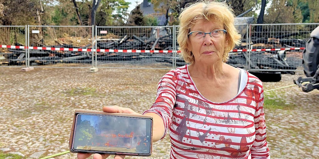 Sigrid Selent zeigt auf ihrem Handy ein Foto vom Vollbrand ihrer Scheune. Im Hintergrund das, was von dem alten Fachwerkbau übrig blieb.