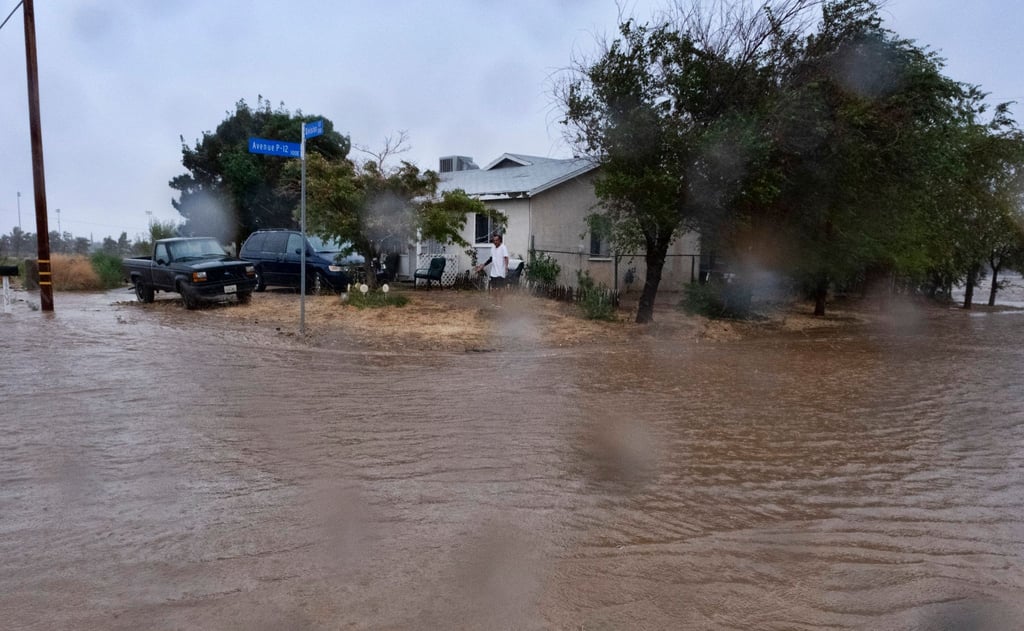 Ein Anwohner prüft während eines Regengusses in Palmdale die Überschwemmungen rund um sein Haus.