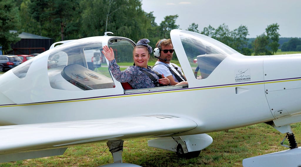 Flugtage in Gardelegen: Fluggast Elnara Köhn winkt Mann und Sohn zum Abschied, bevor sie mit Pilot Bennet Adloff in die Luft geht. Später sagt sie: „Es war wunderschön.“