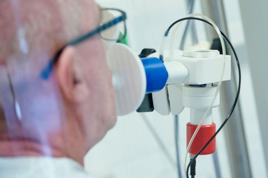 Bei einem ehemaligen Corona-Patienten wird in einer Lungentest-Kabine die Lungenfunktion gemessen.