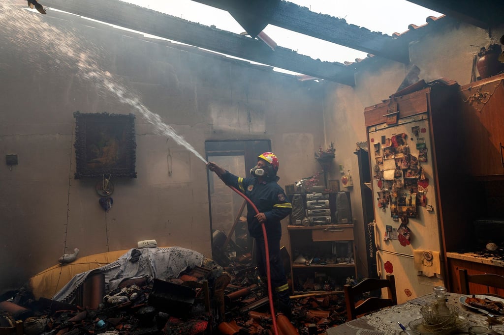 Ein Feuerwehrmann löscht ein Haus im Dorf Hasia in der Nähe von Athen.