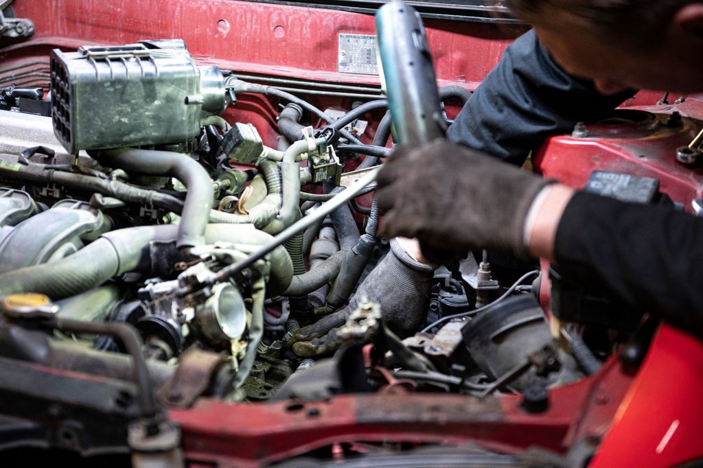 Ein Automechaniker und Besitzer seiner Werkstatt arbeitet an einem Auto.