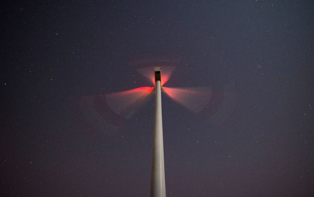 Ein Windrad dreht sich in der Nacht und blinkt.