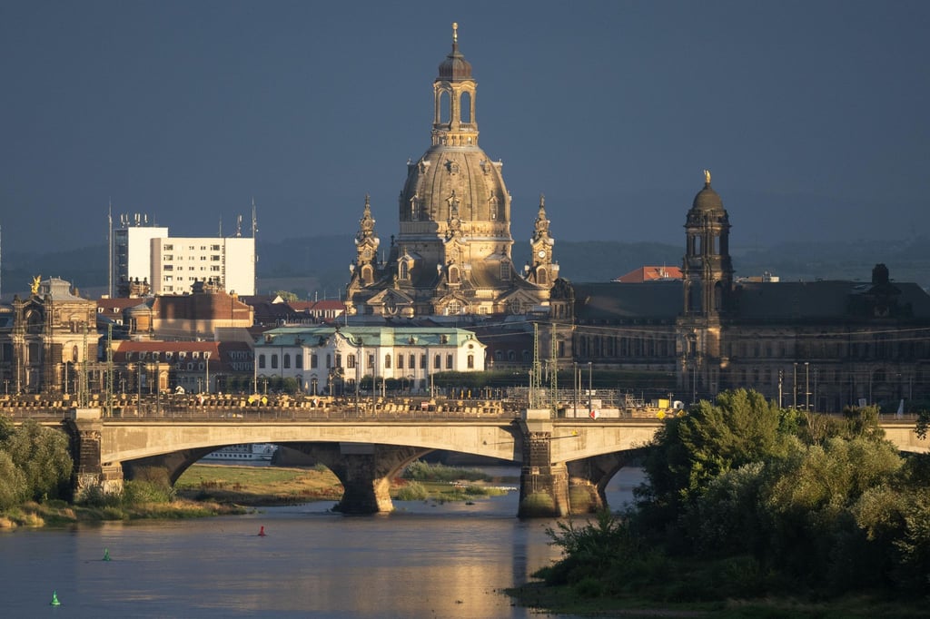 Hell erleuchtet ist die Kulisse der Frauenkirche im Licht der untergehenden Sonne.