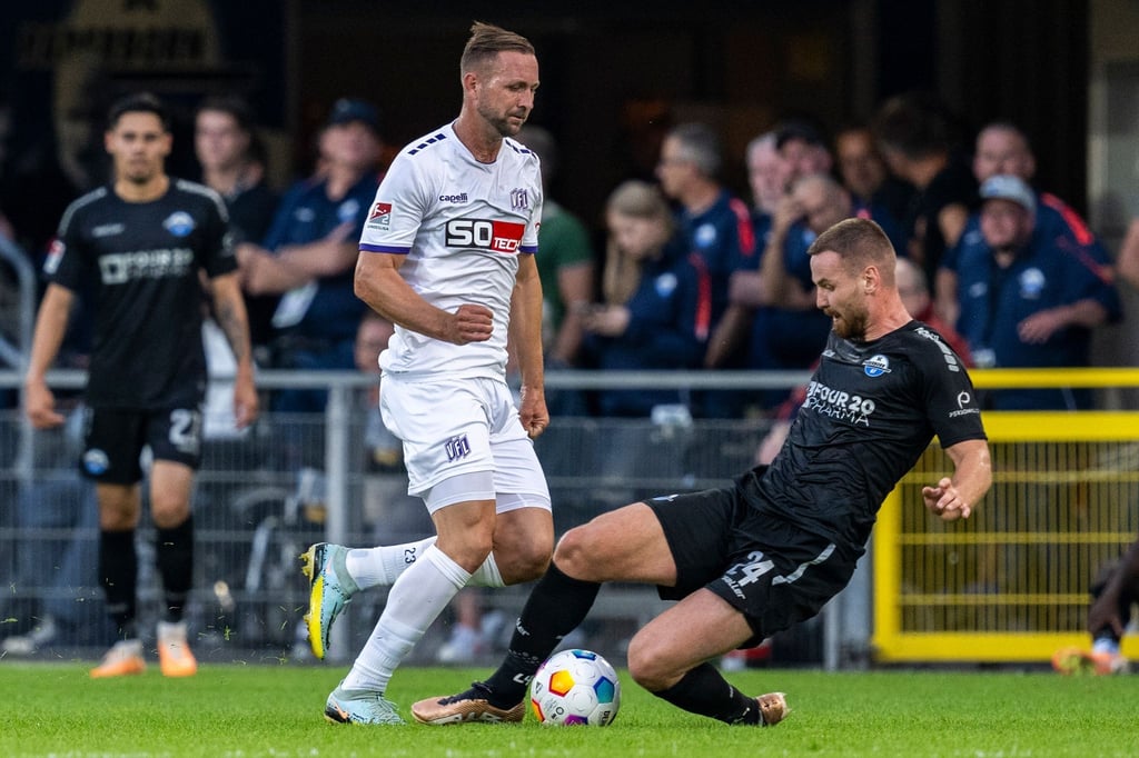 Osnabrücks John Verhoek (M) und Paderborns Jannis Heuer kämpfen um den Ball.