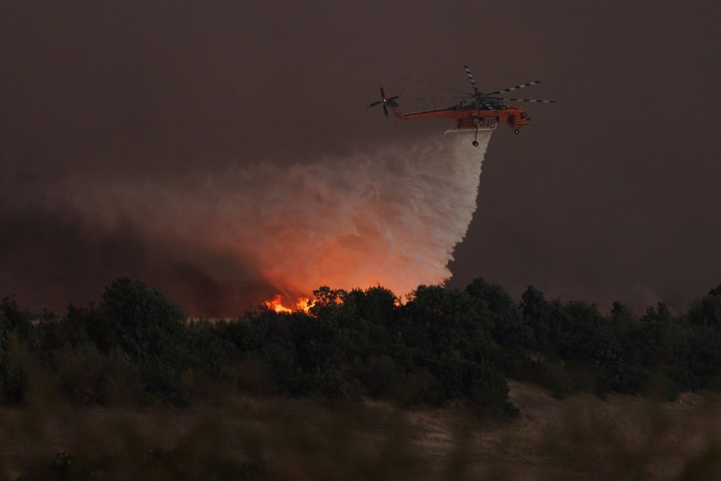 Ein Hubschrauber wirft Wasser über dem Dorf Avantas ab. Stürmische Winde fachen die Flammen der Waldbrände in ganz Griechenland an.