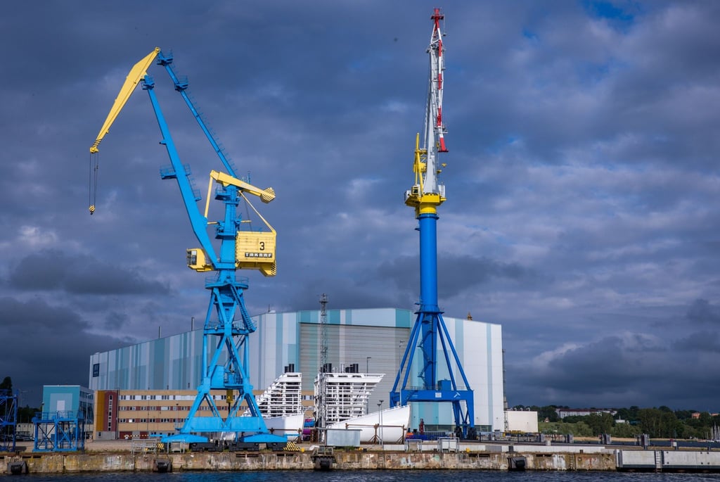 Werftkrane stehen auf dem Gelände der Werft vor der Schiffbauhalle der ehemaligen MV-Werft.
