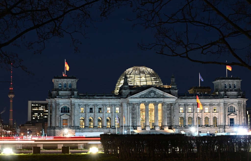 Autolichter hinterlassen nach Einbruch der Dunkelheit Lichtstreifen vor dem Reichstagsgebäude und der beleuchteten Kuppel.