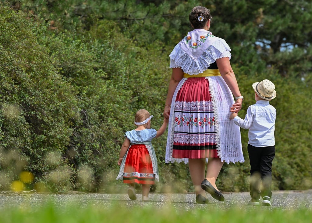 Eine Mutter in sorbisch-wendischer Festtagstracht geht mit ihren Kindern in Heinersbrück spazieren.