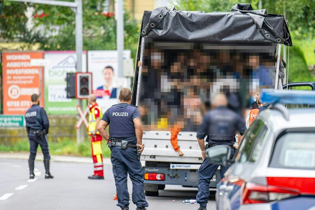 Polizisten stehen bei einer Kontrolle in Österreich an einem Kleintransporter. Die Beamten entdeckten dabei 53 Personen auf der Ladefläche.
