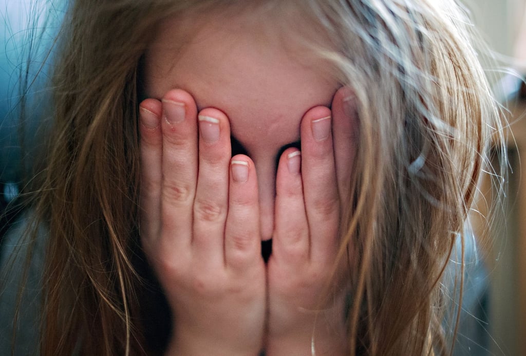 Ein junges Mädchen hält sich die Hände vor ihr Gesicht.