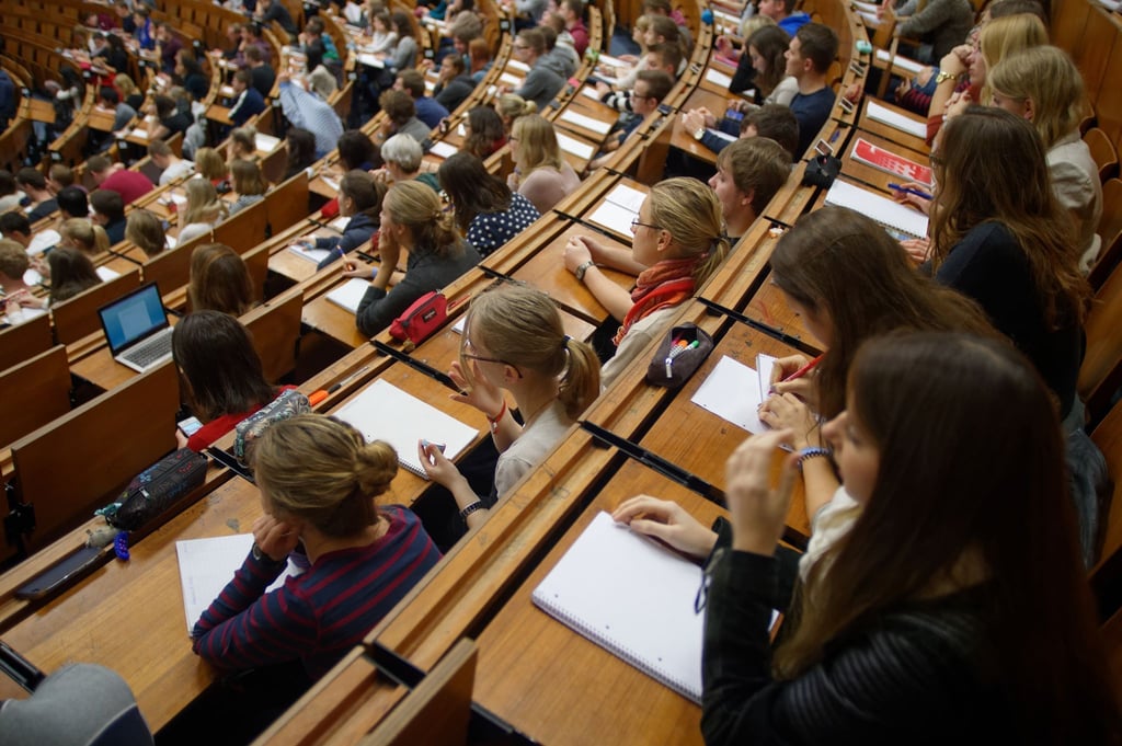 Studenten und Studentinnen sitzen im Hörsaal und verfolgen eine Vorlesung.