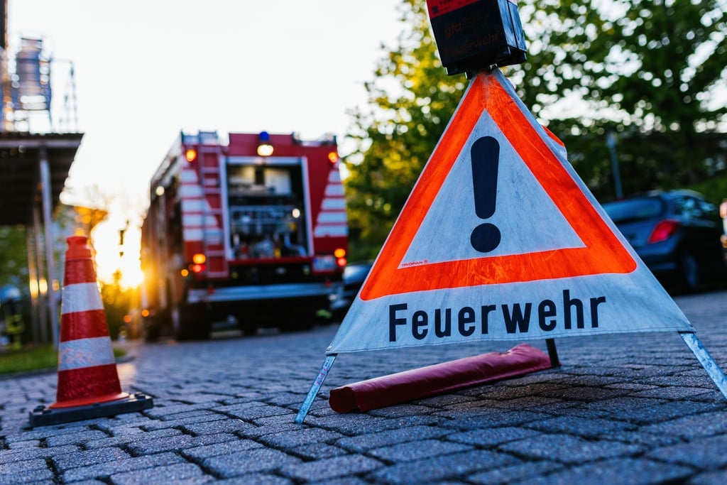 Ein Warndreieick mit der Aufschrift „Feuerwehr“ steht auf dem Hof eines Feuerwehrgerätehauses. In Leipzig hat eine Mülltonne gebrannt.