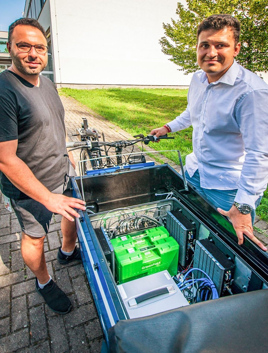 Die wissenschaftlichen Mitarbeiter Mahmoud Laghbani (links) und Dimitar Iliev zeigen die moderne Technik, die im Innenraum des Lastenrades steckt.