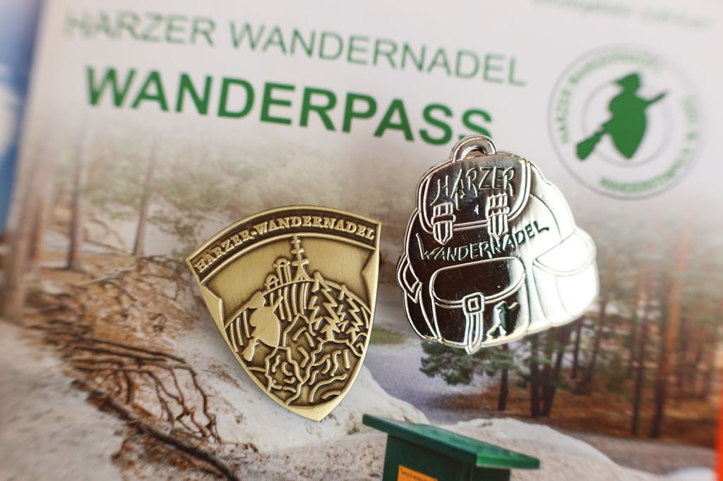 Abzeichen der Harzer Wandernadel liegen auf einem Stempelheft.