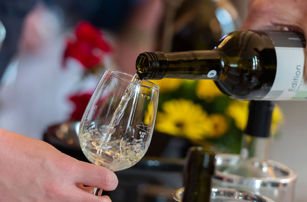 Ein Weinglas wird mit Weißwein befüllt.