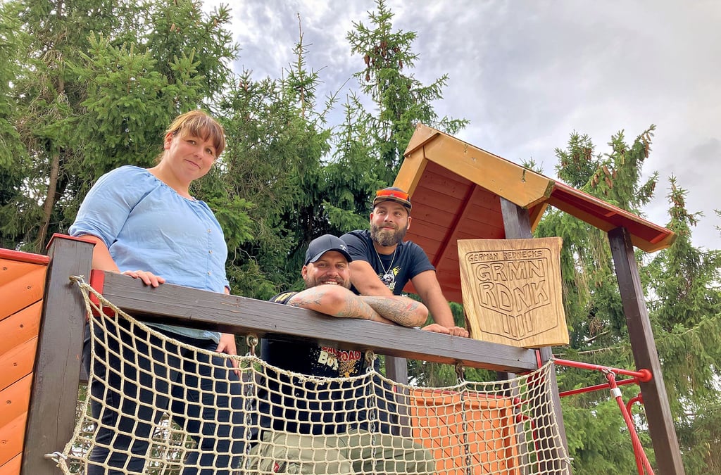 Kita-Leiterin Nadine Hiesener steht mit Anthony Abrantes und Michael Jungmann (v.l.) von den German Rednecks auf einem Klettergerüst der „Hasselborner Zwerge“. Die Einrichtung im Ballenstedter Ortsteil Badeborn soll eine Spende von mehr als 4.000 Euro bekommen.