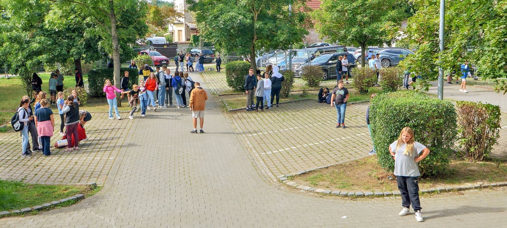 Der provisorische Schulhof der Gemeinschaftsschule in Wanzleben ist auf einem Teil der Parkplätze vor dem Gebäude eingerichtet worden. Hier gibt es allerdings nur drei Bänke, also hocken viele Schüler auf dem Boden.