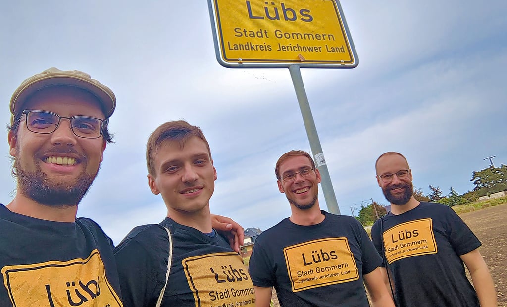 Finn Boie (v.l.), Lukas Kohlrautz, Michael Klais und Tobias Görtz am Ortseingangsschild von Lübs. Die Studienfreunde sind seit drei Jahren dabei, Lübs weltbekannt zu machen. Wo immer sie sind, hinterlassen sie auf markanten Punkten Aufkleber des 320-Seelen-Ortes.