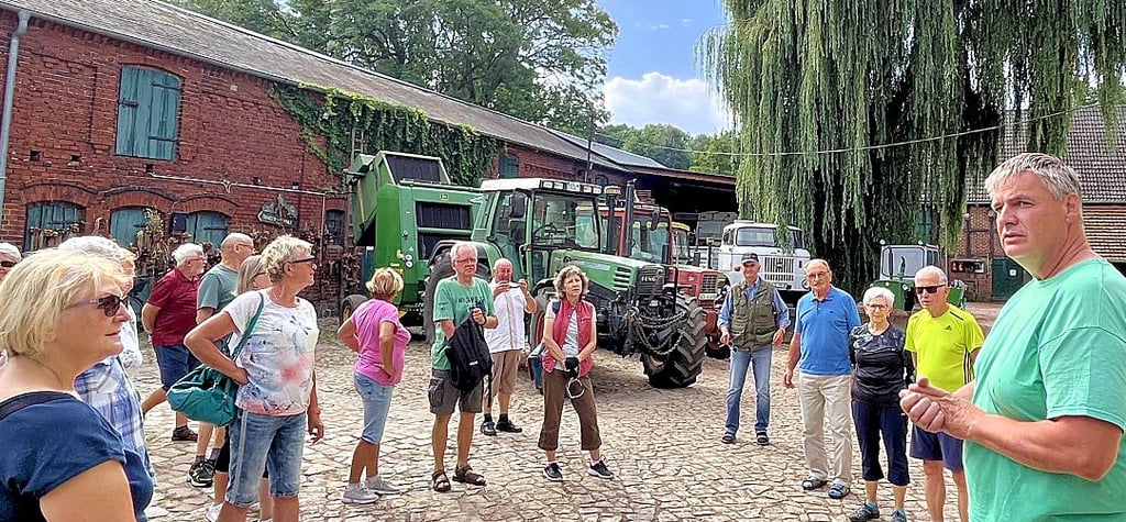 Ökolandwirt Michael Grupe begrüßt die Radfahrer vom Heimatverein aus Tangerhütte an der Tangermühle. Im Hintergrund die Technikausstellung des Betriebs.