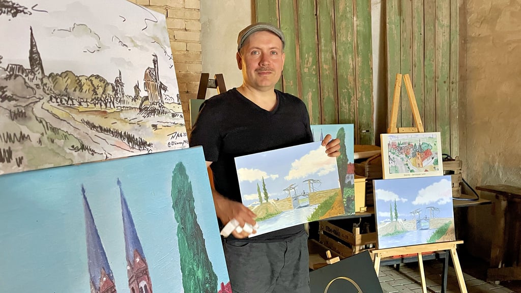 Maler Andreas Müller in der Kunstscheune Steinitz vor seinen Arbeiten.