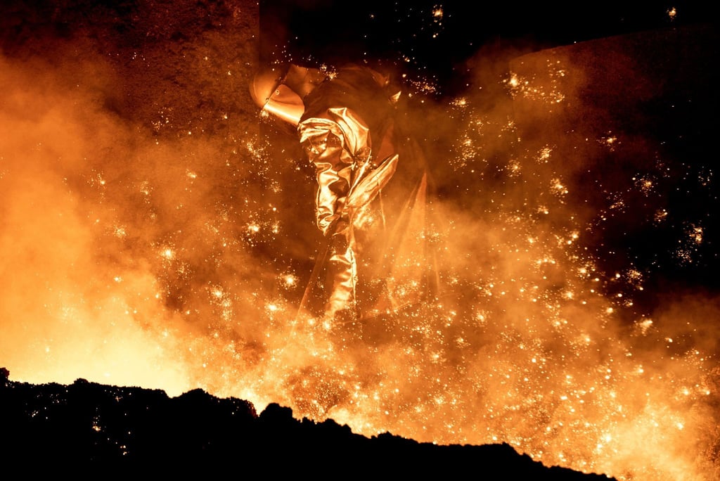 Ein Mitarbeiter reinigt im Stahlwerk der Salzgitter AG die Abstichrinne an einem Hochofen.