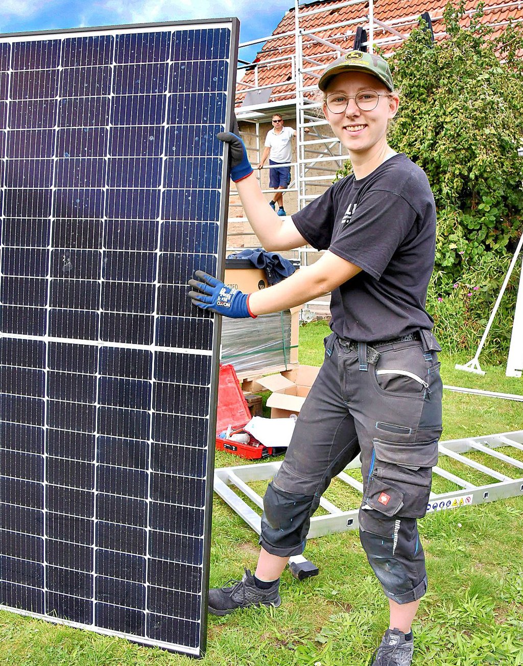 Elisabeth Frehe bringt als auszubildende Mechanikerin im ersten Lehrjahr Solarmodule auf einer Baustelle auf das Dach eines Einfamilienhauses.