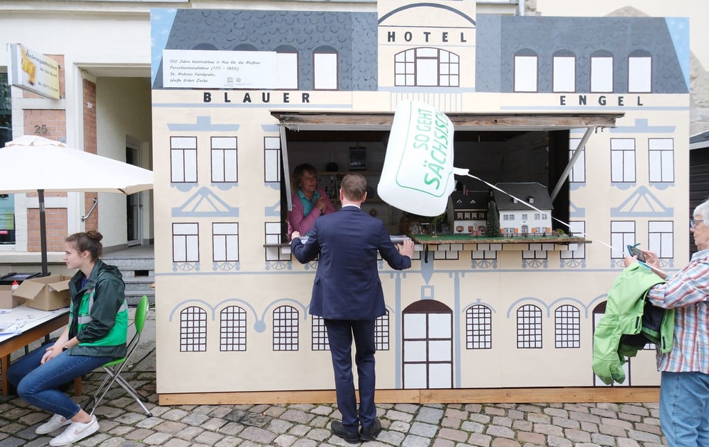 Michael Kretschmer (CDU, M), Ministerpräsident des Landes Sachsen, steht an einem Stand des Auer Hotels „Blauer Engel“.