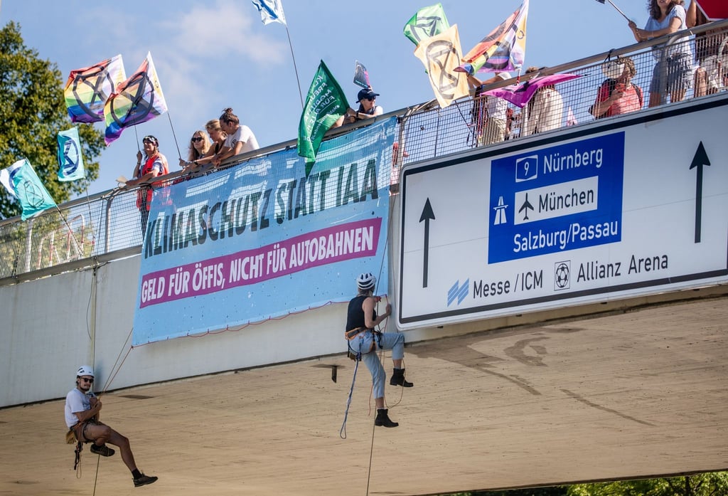 Klimaaktivisten von Extinction Rebellion seilen sich in München von einer Brücke ab.