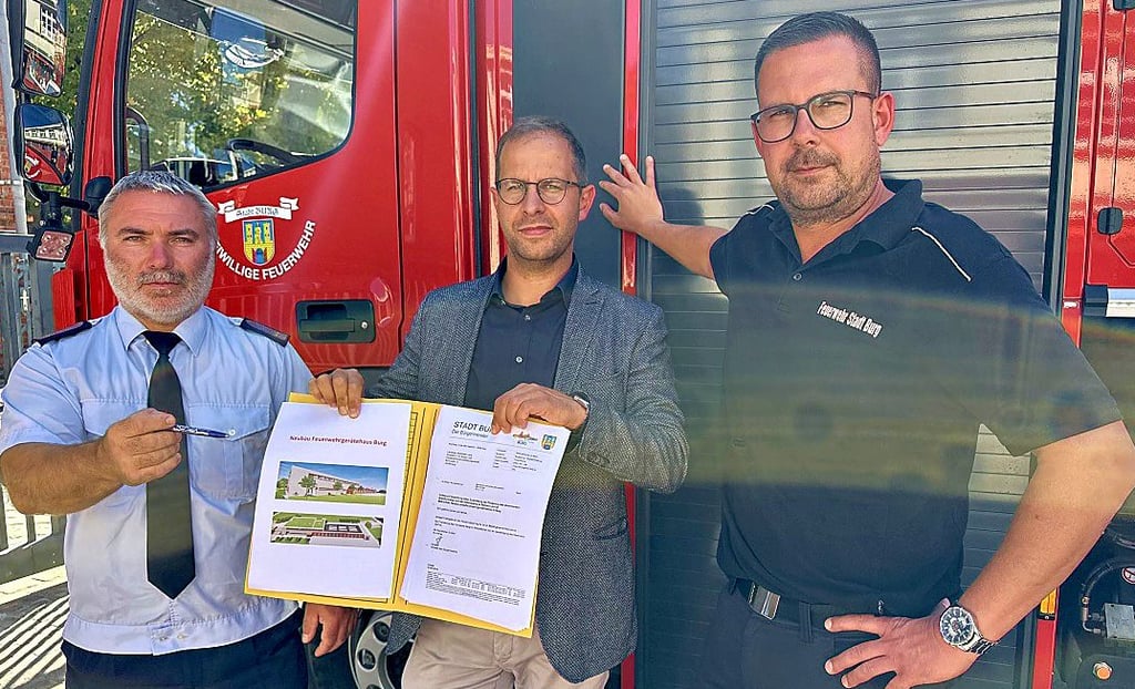 Bürgermeister Philipp Stark zeigt mit Stadtwehrleiter Maik Friedrich (l.) und Ortswehrleiter Jens Wiedemann auf den Fördermittelantrag für den Bau des neuen Gerätehauses.