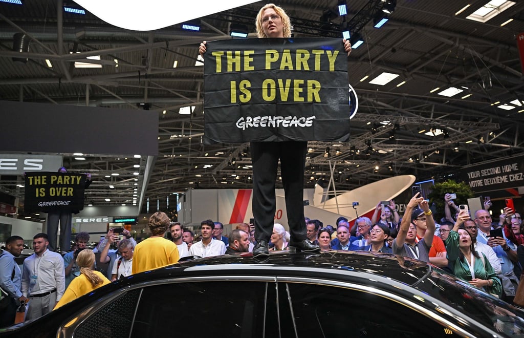 Eine Greenpeace-Aktivistin bei der Eröffnung der IAA auf dem Dach eines ausgestellten Autos.