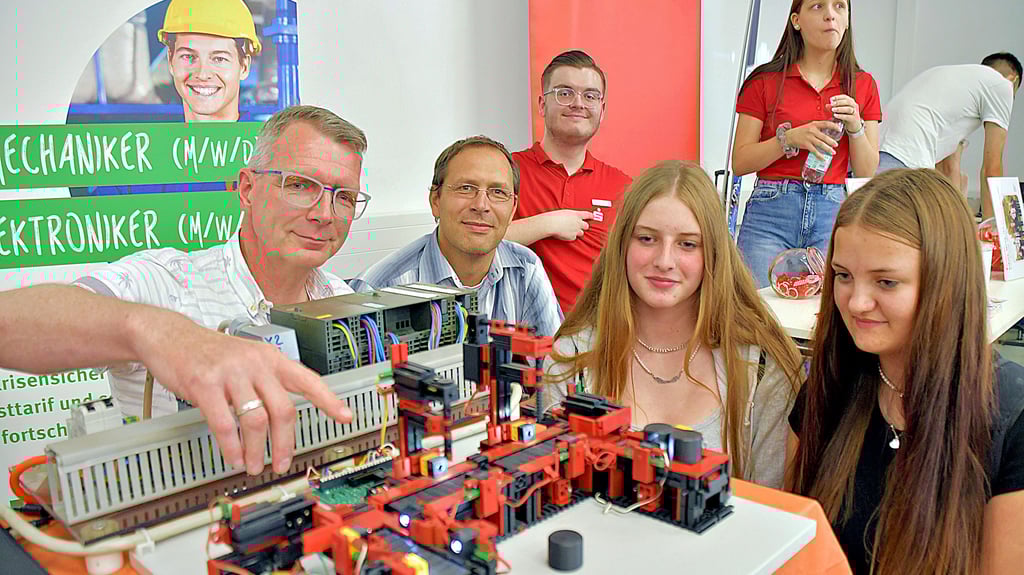 An einem Modell erklären Markus Bühnemann (l.) und Thomas Reibiger, wie technische Produktionsabläufe beim Calvörder Getränkehersteller Refresco an einem Laufband funktionieren. Interessiert verfolgen Katharina Schlordt (r.) und Lena Straub aus der Oebisfelder Drömlingschule den Ausführungen der beiden Ausbilder.