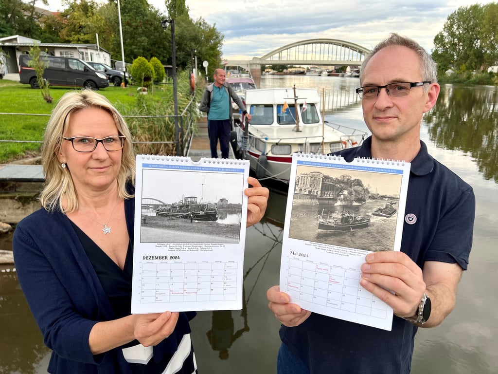 Jana Krätzig und Andreas Wehlmann zeigen den neuen Wandkalender des Alslebener Schiffervereins „Undine“.