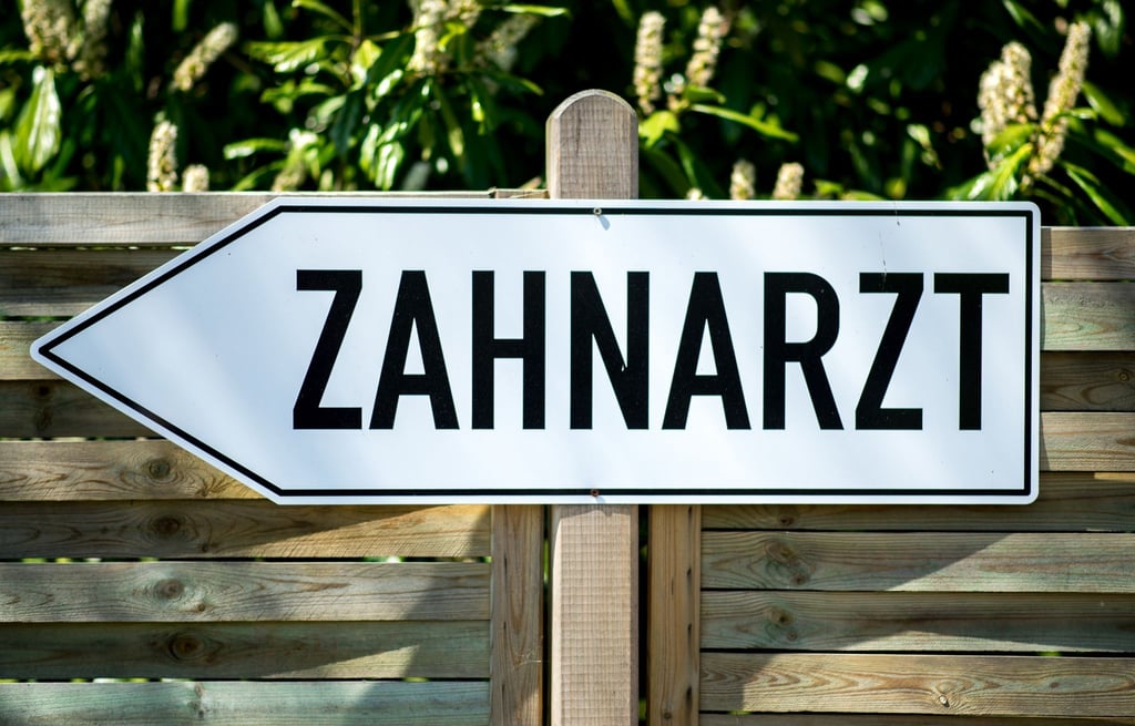 Ein an einem Zaun befestigtes Schild mit der Aufschrift „Zahnarzt“.