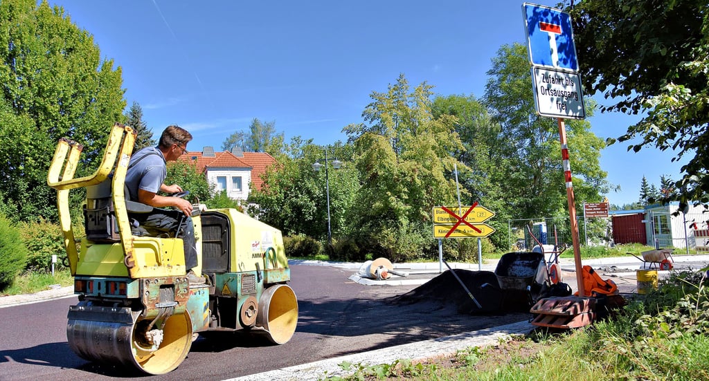 Thomas Hoppe von der Firma Kühne Asphaltbau lenkt am Kreisverkehr in Elend die Straßenwalze, mit der Split eingebracht wird. Foto: Katrin Schröder