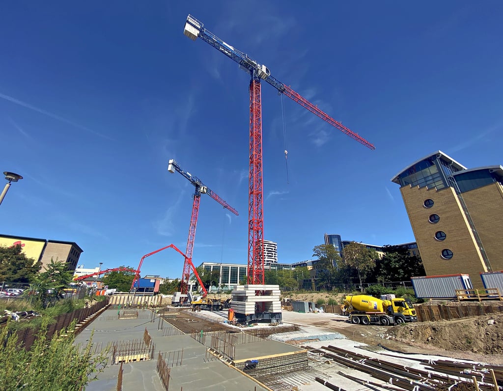 Blick über die Baustelle im nördlichen Stadtzentrum. Betonpumpen und zwei Turmdrehkräne bestimmen das Bild.