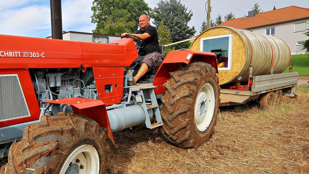 Kevin Launicke am Steuer seines Traktors, dahinter der ungewöhnliche Wohnwagen.