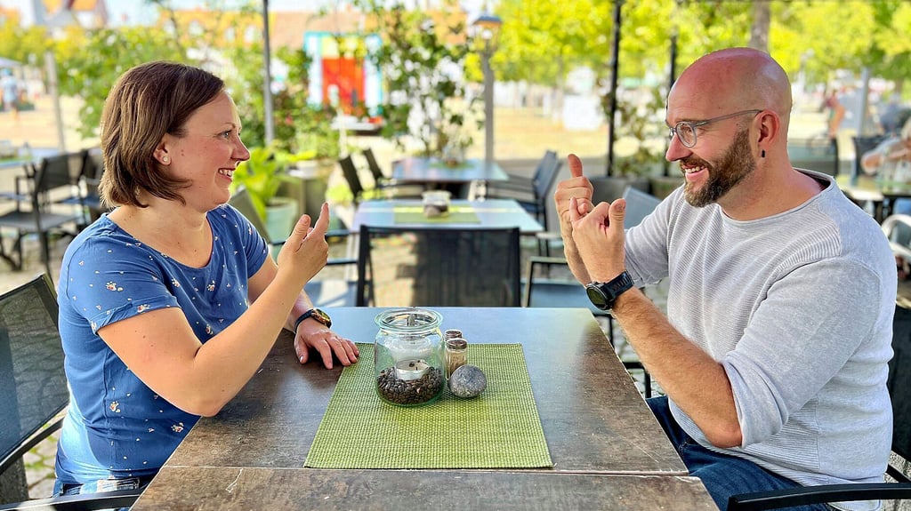 Bianca Ewald, Dolmetscherin für Gebärdensprache aus Neundorf, und Henry Niekrawietz, Dozent für Gebärdensprache und selbst taub, unterhalten sich im Café.