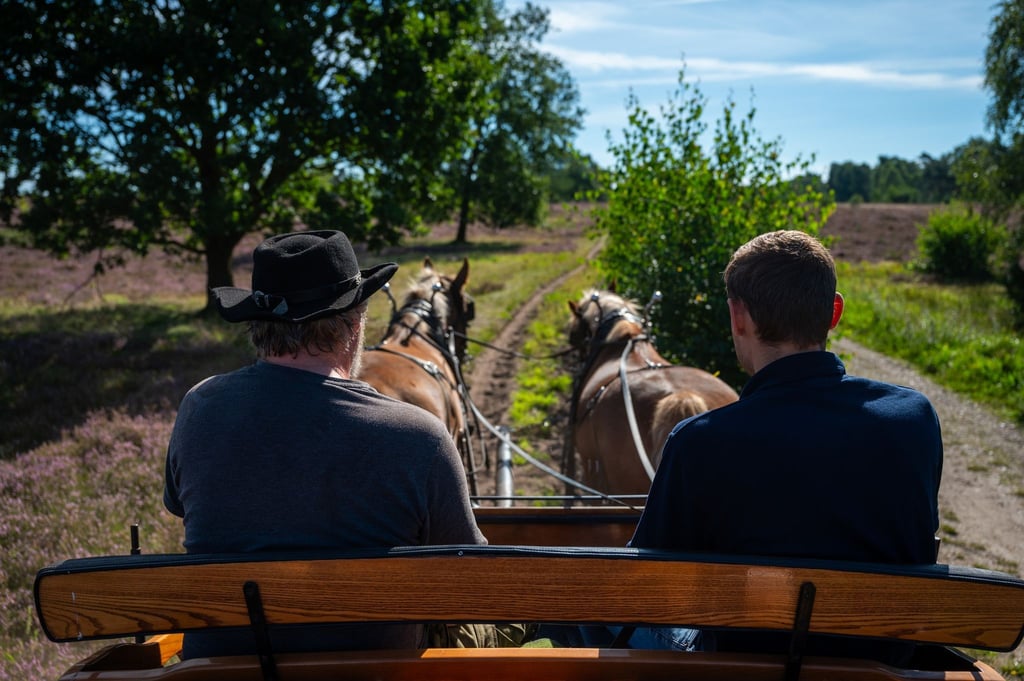 Burkhardt Hoppe (l) und Steffen Meyer fahren mit einer Kutsche durch die Heide.