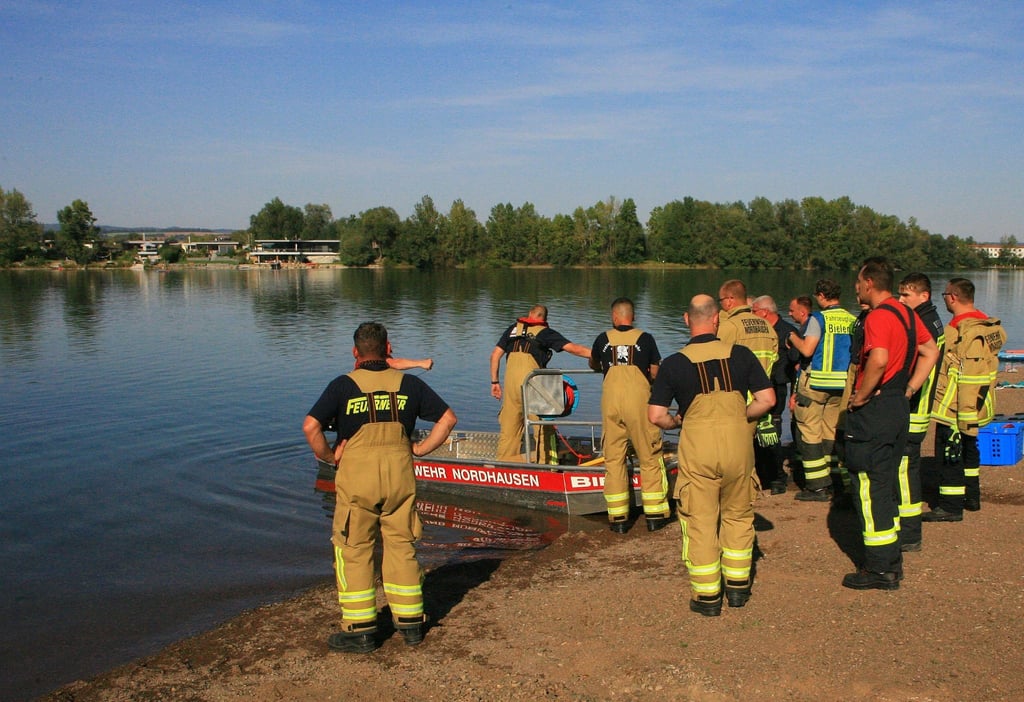 Einsatzkräfte der Feuerwehr stehen am Sundhäuser See.