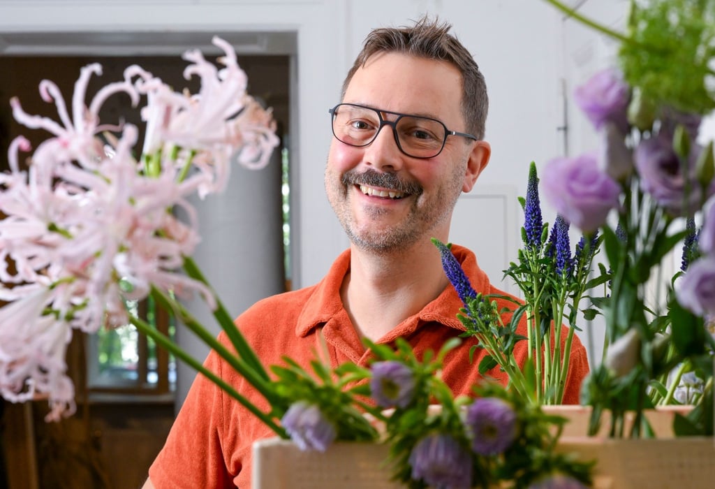 Der Florist Nicolaus Peters steht hinter Blumen.