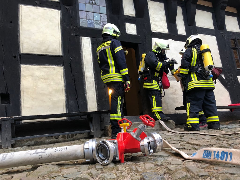 Mit Atemschutzgeräten ausgestattet, betreten die Einsatzkäfte vom Innenhof der Burg aus die verrauchte Küche.