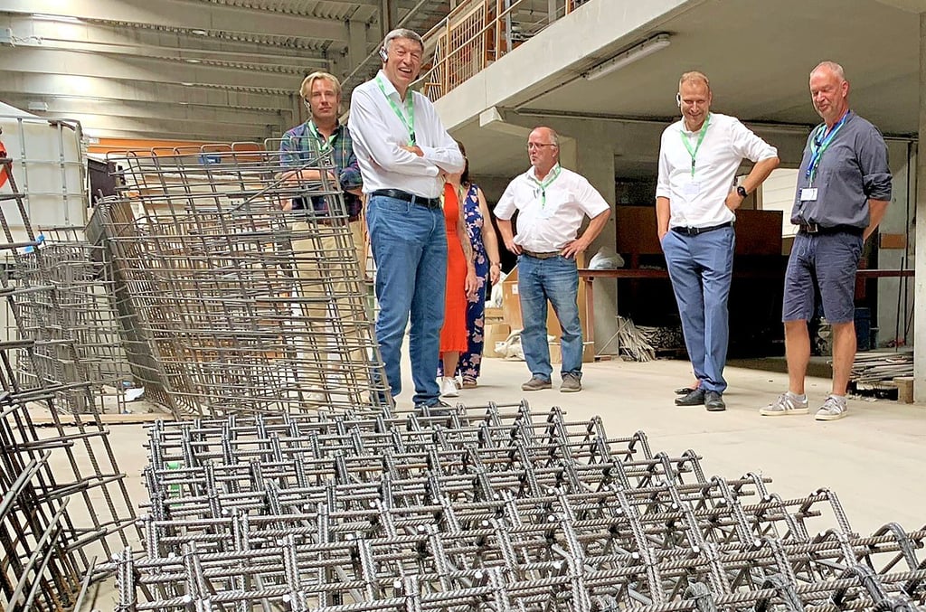 Eckhardt Thomas (2.v.l.) steht beim Rundgang mit Gästen vor Armierungen für Treppen aus Beton.