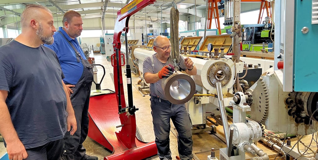 Geschäftsführer Markus Weissgärber in der nach der Flut von 2013 neu errichteten Produktionshalle. Thomas Pioch und Peter Brudniok (von links) richten gerade den schweren Extruderkopf neu ein.